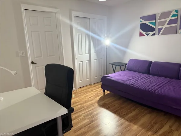 a bedroom with a bed chair and wooden floor
