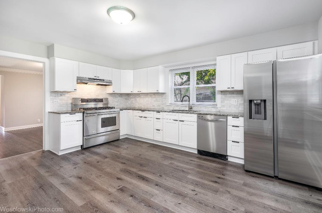 7700 Garden Lane Justice, IL 60458 - Photo 5 of 17 a kitchen with stainless steel appliances granite countertop a stove a sink dishwasher a refrigerator and white cabinets with wooden floor