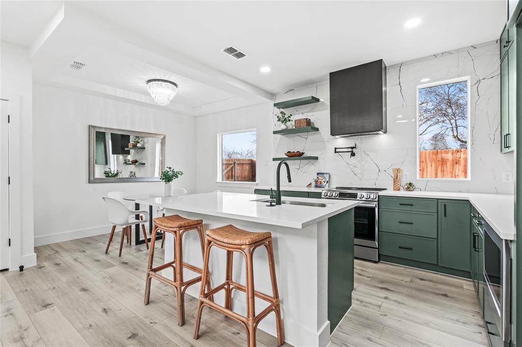 4712 Garrison Street Dallas, TX 75216 - Photo 14 of 30 Kitchen with green cabinets, electric stove, backsplash, a kitchen bar, and light stone countertops