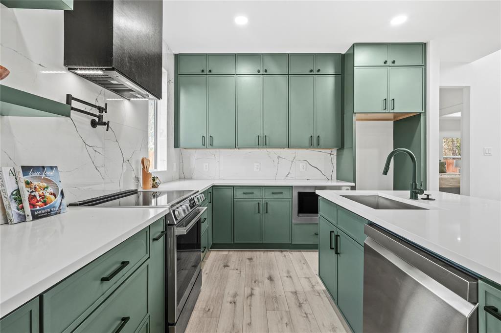 4712 Garrison Street Dallas, TX 75216 - Photo 15 of 30 Kitchen with green cabinets, stainless steel appliances, custom range hood, light stone countertops, and light wood-style floors