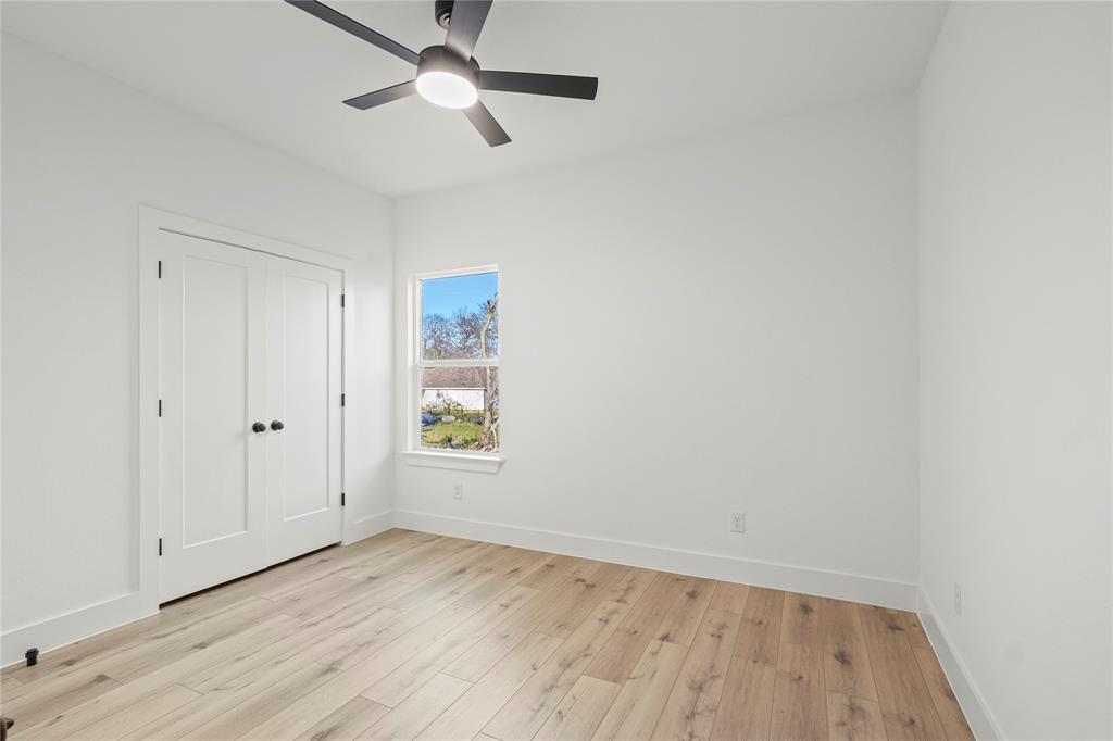 4712 Garrison Street Dallas, TX 75216 - Photo 27 of 30 Unfurnished bedroom featuring light wood finished floors, ceiling fan, and a closet
