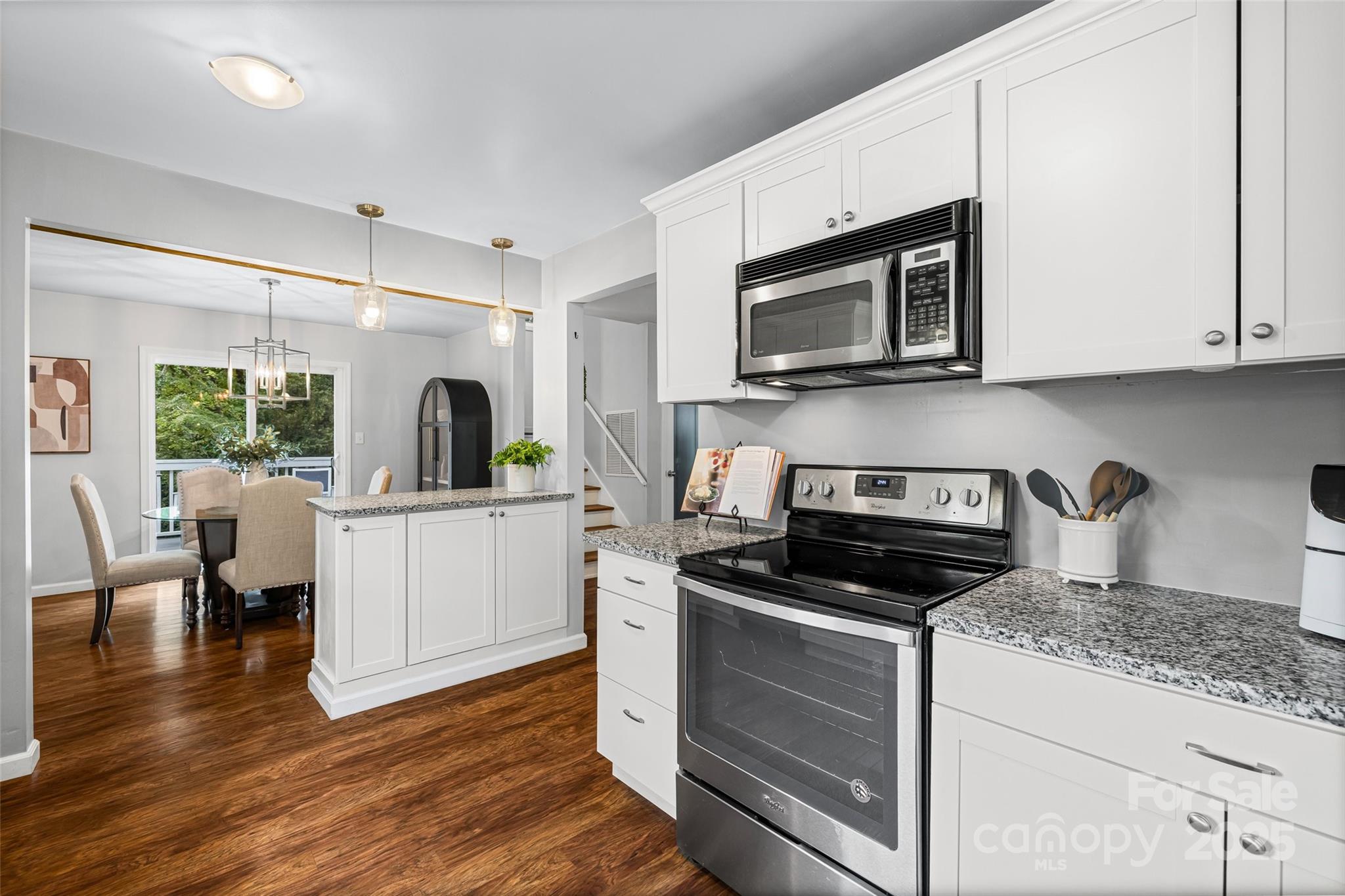 6027 Windjammer Drive Tega Cay, SC 29708 - Photo 7 of 34 a kitchen with stainless steel appliances kitchen island granite countertop a stove a sink and a microwave