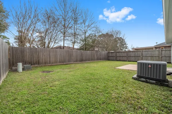 a view of a backyard with a fence and large trees