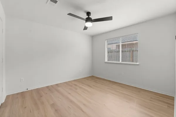 a view of empty room with wooden floor and ceiling fan