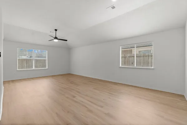 a view of an empty room with a window and wooden floor