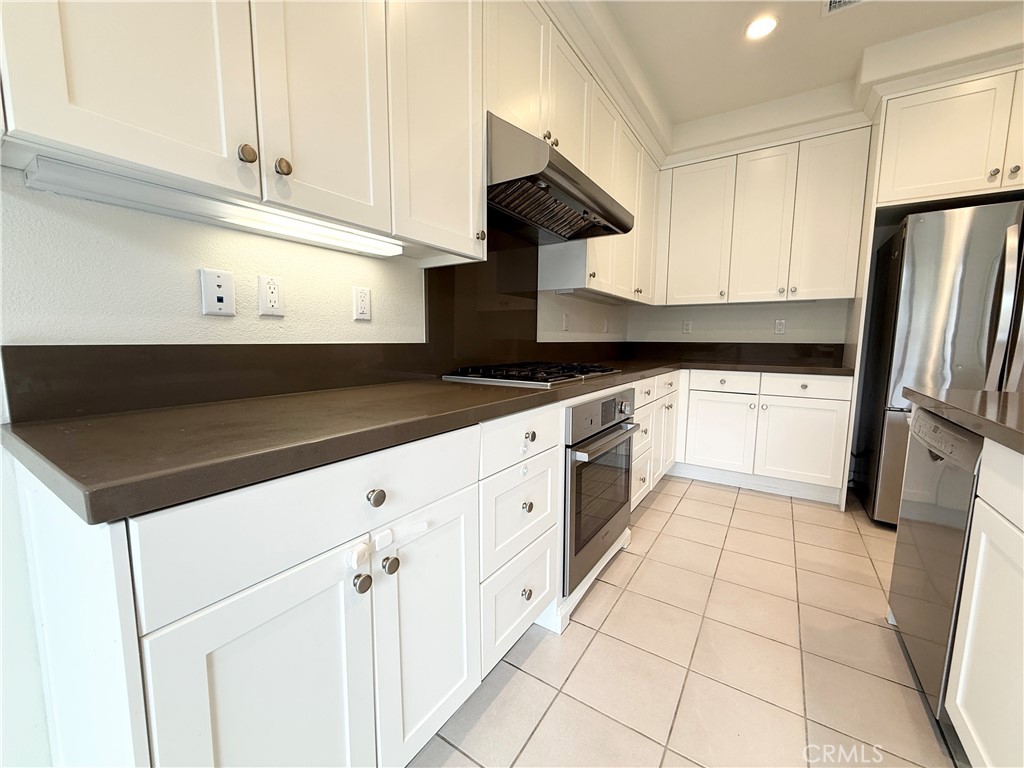 126 Okra Irvine, CA 92618 - Photo 8 of 26 a kitchen with granite countertop white cabinets white stainless steel appliances and a sink