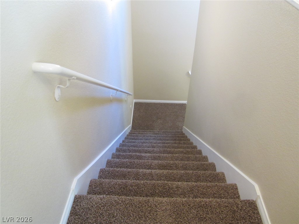 7701 West Robindale Road, Unit 262 Las Vegas, NV 89113 - Photo 6 of 26 A well-maintained staircase features carpeted treads and a practical wall-mounted handrail.
