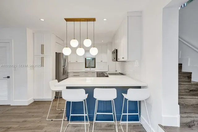 a kitchen with a dining table chairs and wooden floor