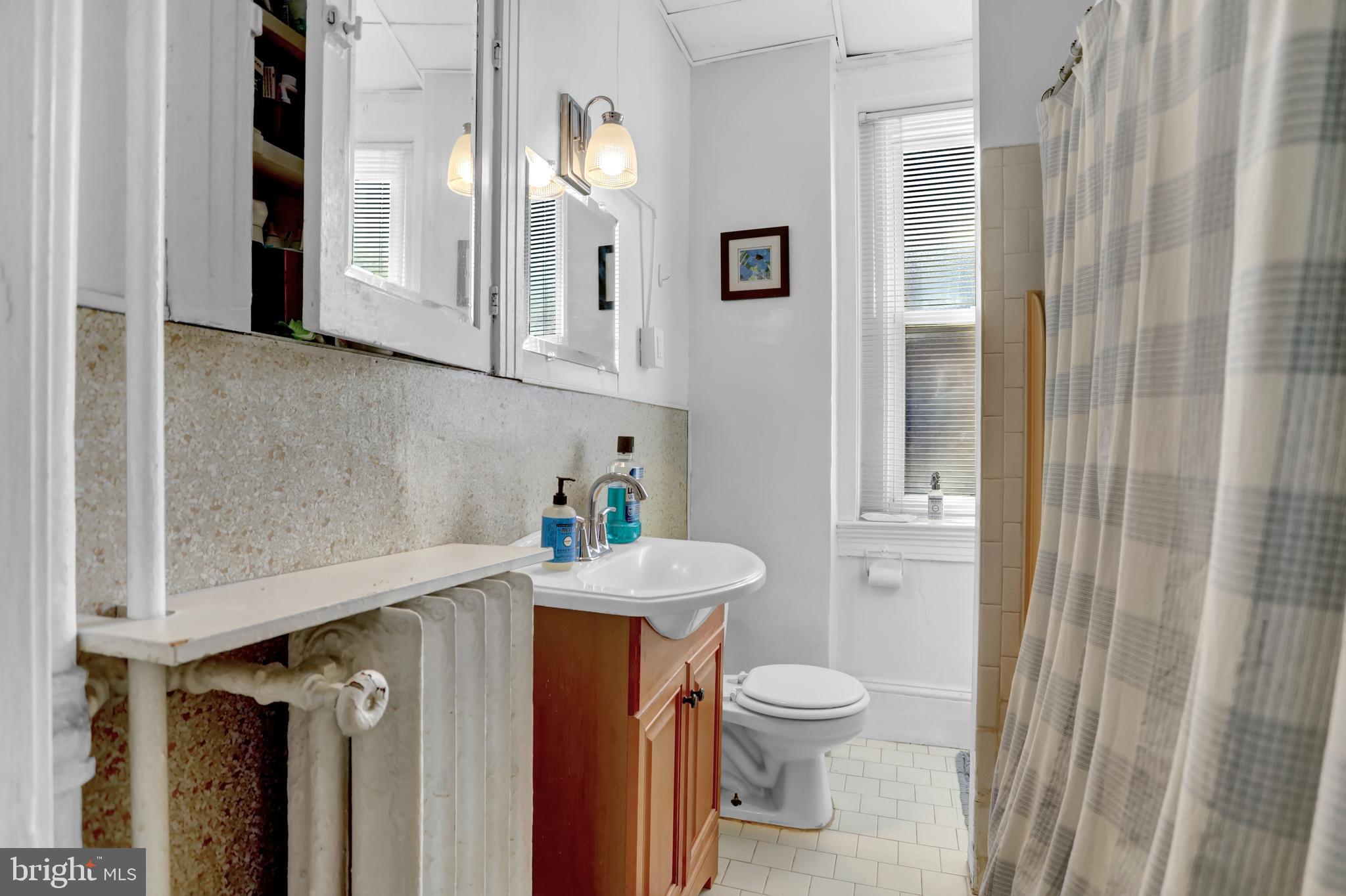 3001 North Calvert Street Baltimore, MD 21218 - Photo 19 of 44 a bathroom with a sink a toilet and shower curtain