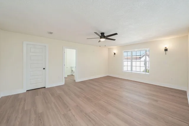 a view of empty room with wooden floor and fan