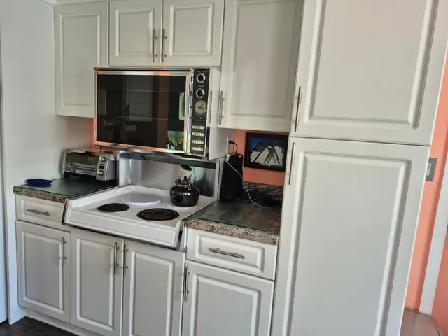 a kitchen with granite countertop white cabinets and white appliances