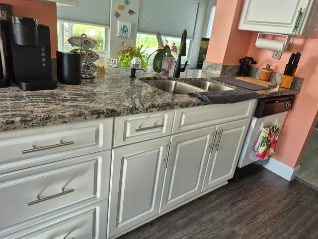 a kitchen with white cabinets and sink