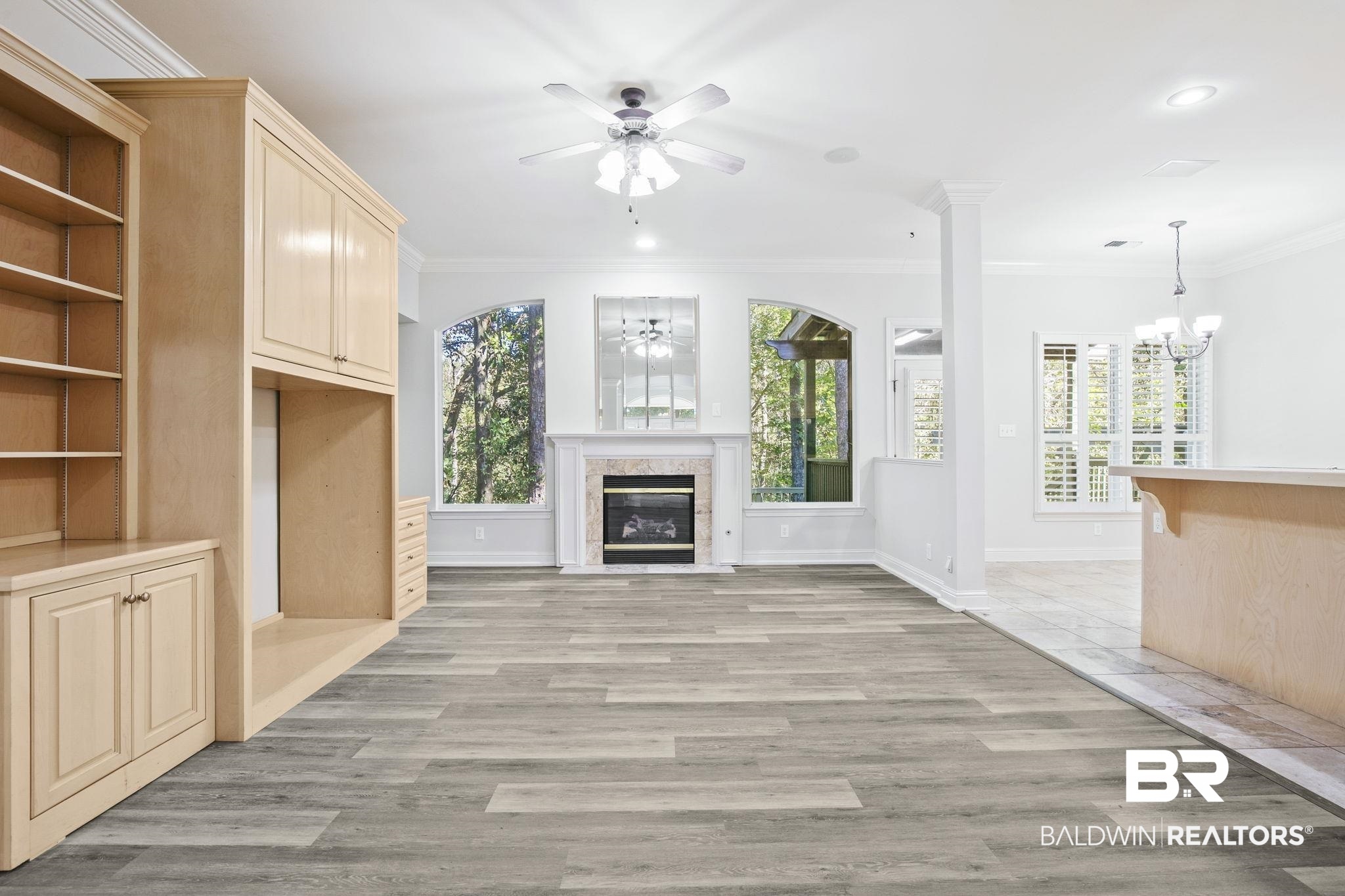 13 Bugle Retreat Daphne, AL 36527 - Photo 6 of 40 Unfurnished living room featuring ceiling fan with notable chandelier, light hardwood / wood-style floors, and ornamental molding