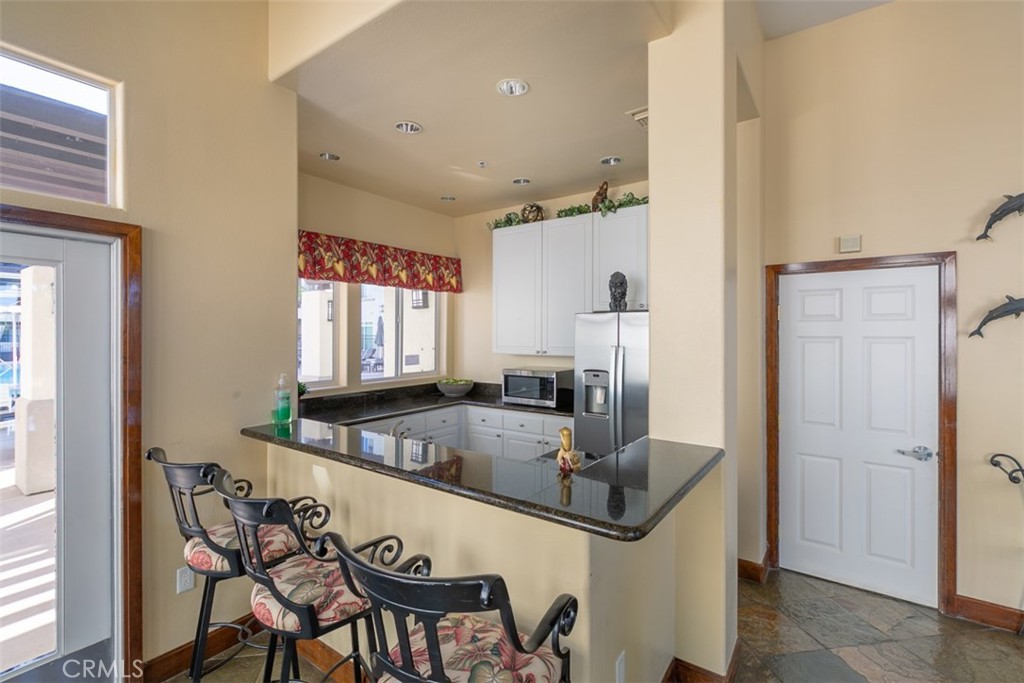 9293 Regents Road, Unit C303 La Jolla, CA 92037 - Photo 18 of 26 a kitchen with granite countertop a table chairs refrigerator and sink