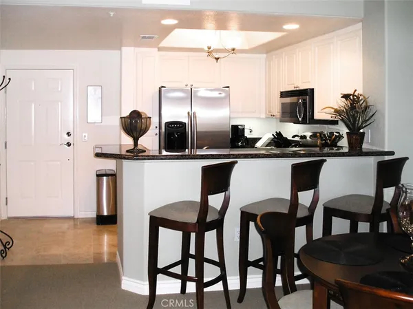 a kitchen with stainless steel appliances a table chairs and a refrigerator