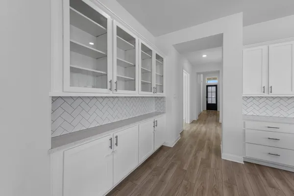 a kitchen with white cabinets and wooden floor
