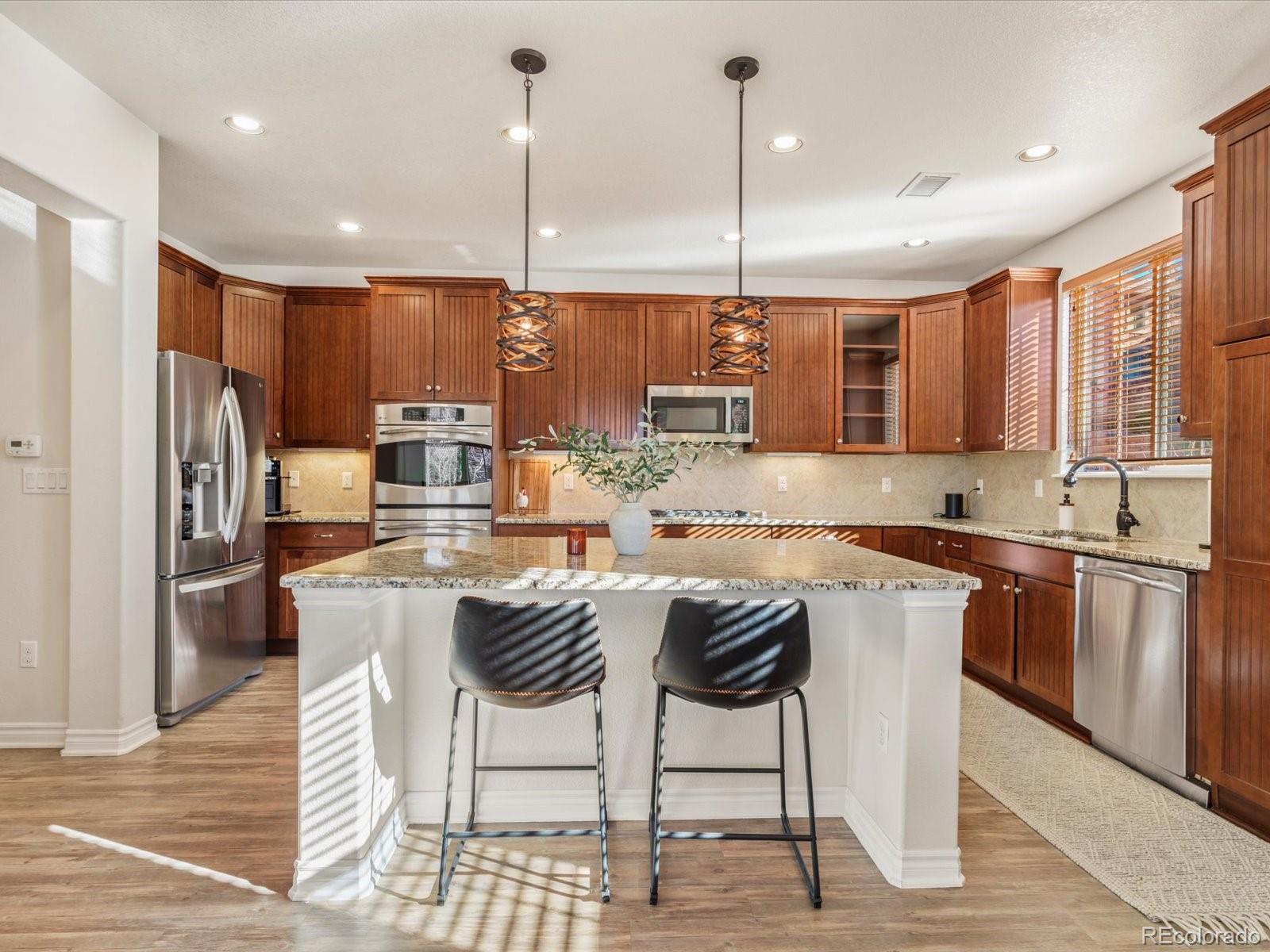 9340 Sori Lane Highlands Ranch, CO 80126 - Photo 12 of 42 a kitchen with stainless steel appliances granite countertop a kitchen island a stove a sink cabinets and a refrigerator