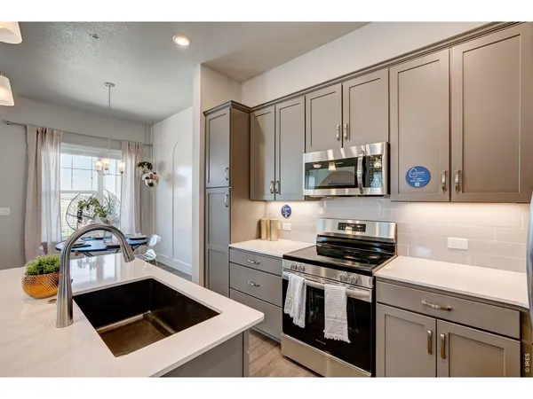 a kitchen with a sink dishwasher a dining table and chairs with wooden floor