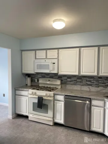 a kitchen with white cabinets and appliances