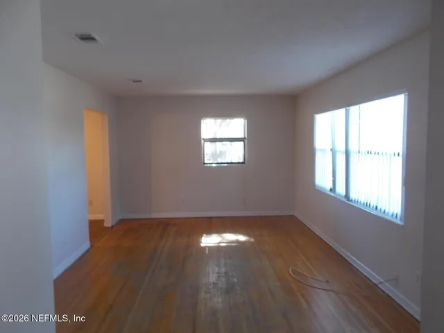 a view of empty room with wooden floor and fan