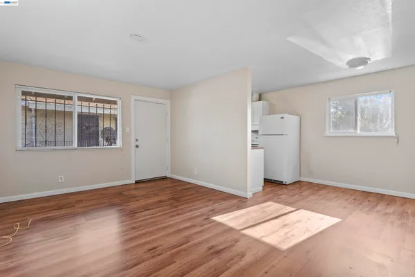 a view of an empty room with window and wooden floor