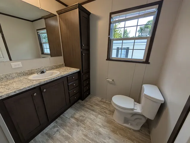 a bathroom with a granite countertop toilet sink and mirror