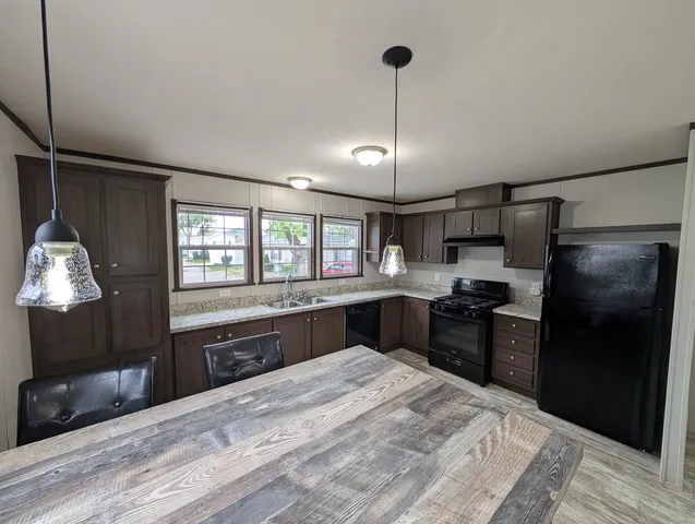 a kitchen with stainless steel appliances kitchen island granite countertop a refrigerator and a sink