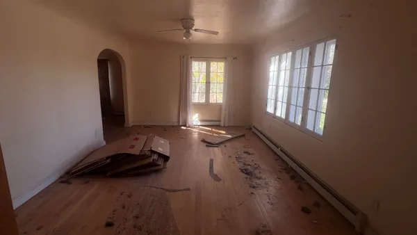 an empty room with wooden floor and windows