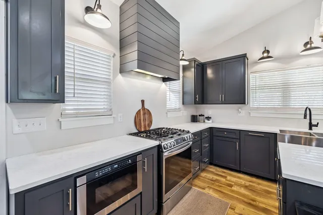 a kitchen with stainless steel appliances granite countertop a sink stove and cabinets