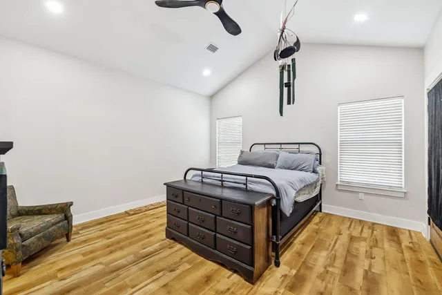 a spacious bedroom with a bed and wooden floor