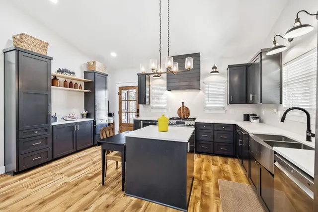 a kitchen with stainless steel appliances kitchen island granite countertop a sink stove and refrigerator