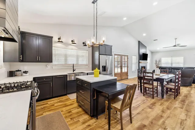 a kitchen with stainless steel appliances granite countertop a stove a sink a dining table and chairs