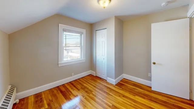 a view of an empty room with wooden floor and closet