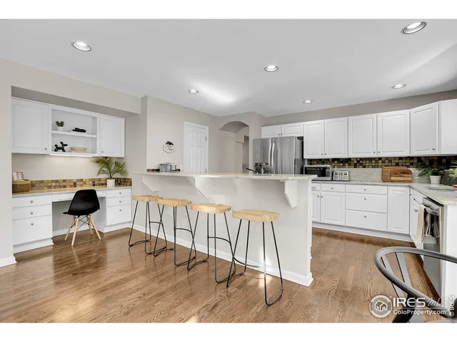 a kitchen with stainless steel appliances granite countertop a refrigerator a stove a sink dishwasher and white cabinets with wooden floor