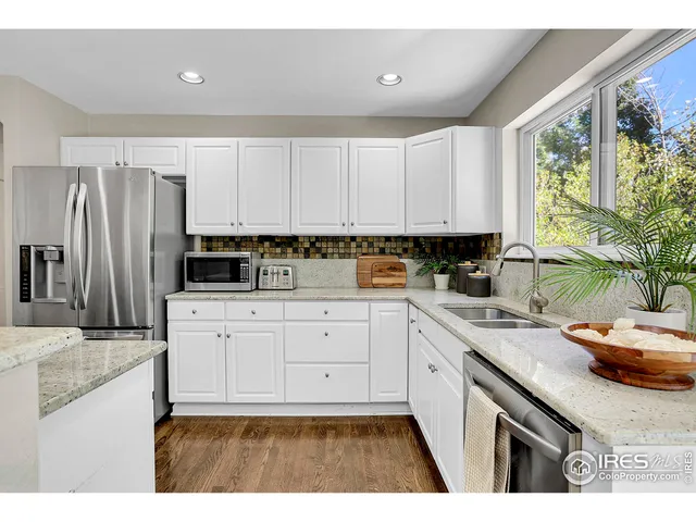 a kitchen with stainless steel appliances granite countertop a sink a stove a refrigerator a counter space and cabinets