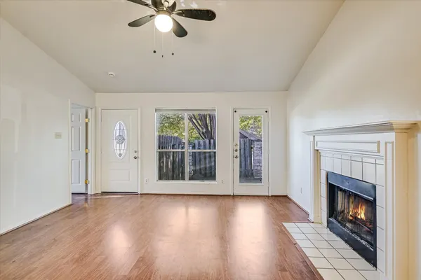 a view of an empty room with wooden floor and a fireplace