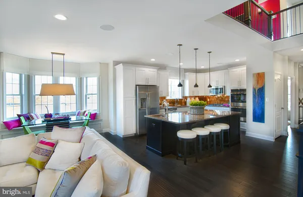 a kitchen with stainless steel appliances kitchen island granite countertop a dining table chairs sink refrigerator and cabinets