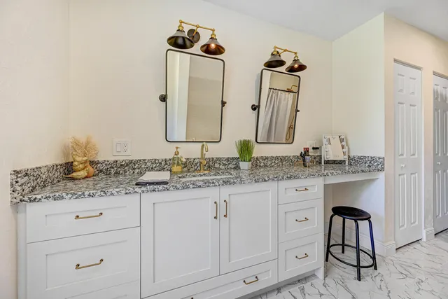 a bathroom with a granite countertop sink and a mirror