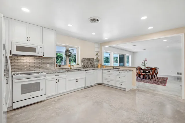 a large white kitchen with white cabinets and stainless steel appliances