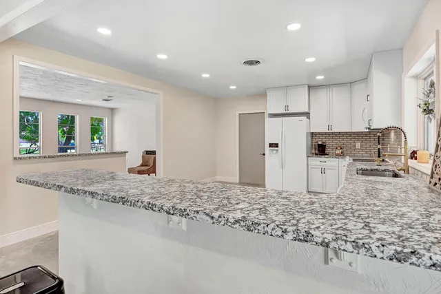 a kitchen with stainless steel appliances granite countertop a sink refrigerator and cabinets