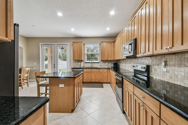 a large kitchen with stainless steel appliances granite countertop a large window and a counter space