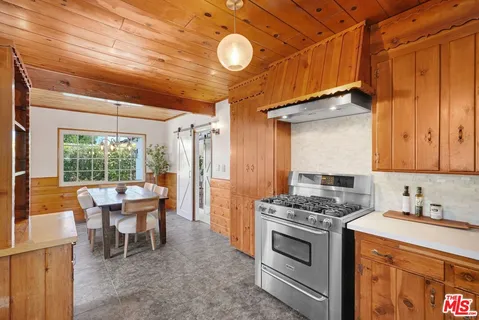 a kitchen that has a lot of stainless steel appliances wooden floor and cabinets