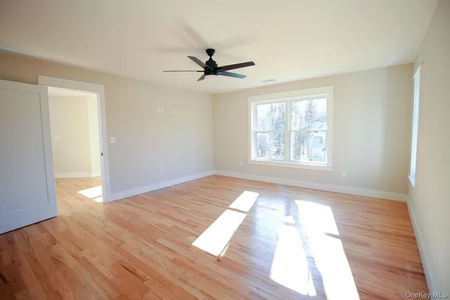 a view of empty room with wooden floor and fan