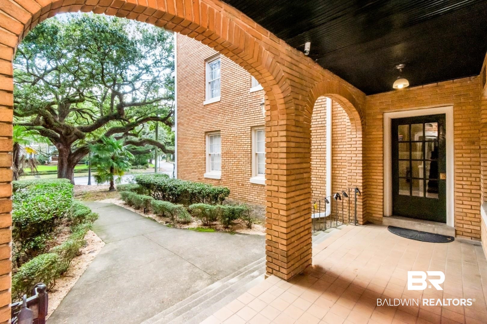 1602 Government Street, Unit 1A Mobile, AL 36604 - Photo 3 of 24 View of exterior entry featuring brick siding and a patio
