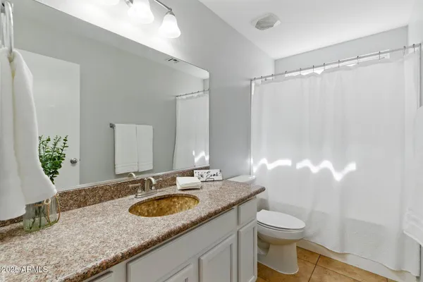 a bathroom with a granite countertop sink a toilet and a mirror