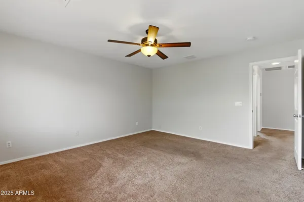 an empty room with chandelier fan and windows