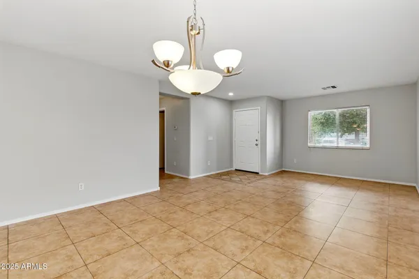 a view of an empty room with a window and chandelier fan