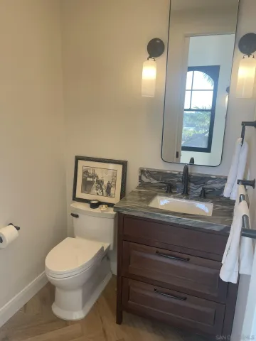 a bathroom with a granite countertop toilet sink and mirror