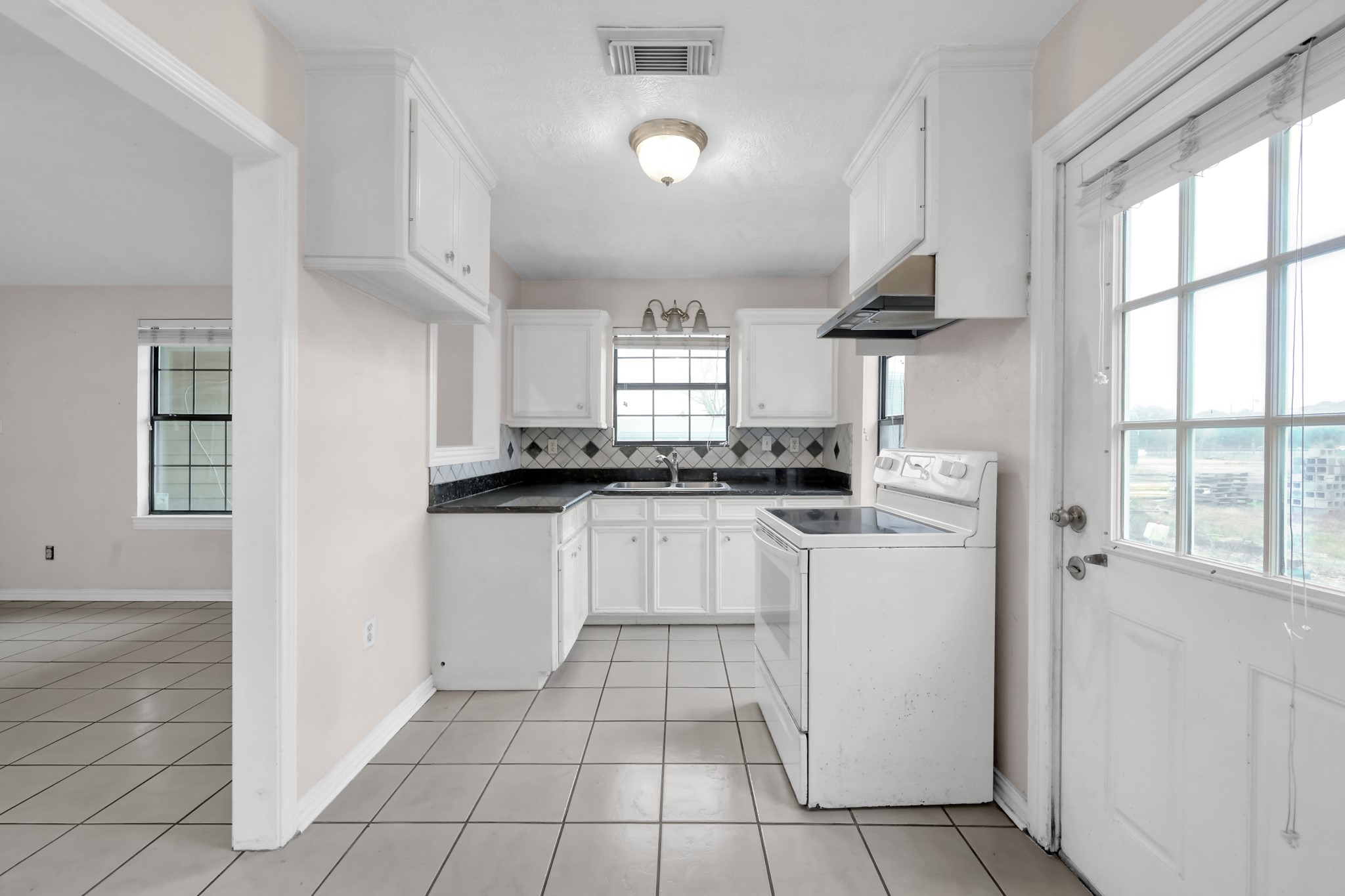 7644 Spring Cypress Road Spring, TX 77379 - Photo 17 of 28 a kitchen with white cabinets a sink a window and appliances