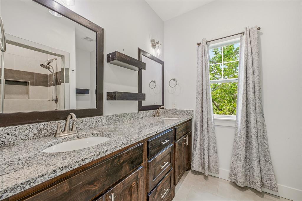 745 North Miller Avenue Stephenville, TX 76401 - Photo 25 of 31 Dual vanity with granite countertop, dark wood-finish cabinetry, and brushed nickel fixtures